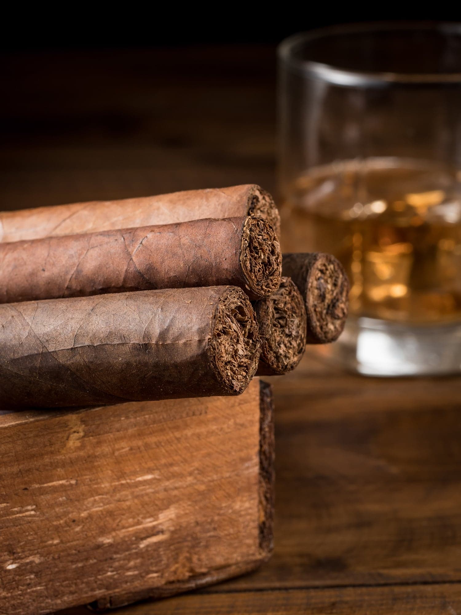 Ausgewählte Zigarren auf einem Holztisch neben einem Glas Whisky
